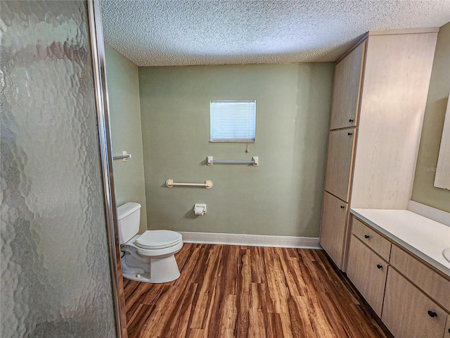 bathroom featuring vanity, a textured ceiling, hardwood / wood-style flooring, and toilet