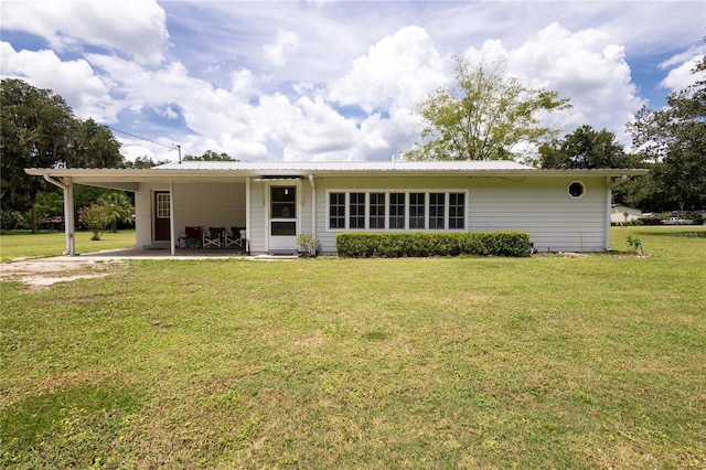 rear view of property featuring a carport and a yard