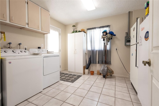 clothes washing area featuring light tile patterned flooring, washing machine and clothes dryer, cabinets, and a textured ceiling