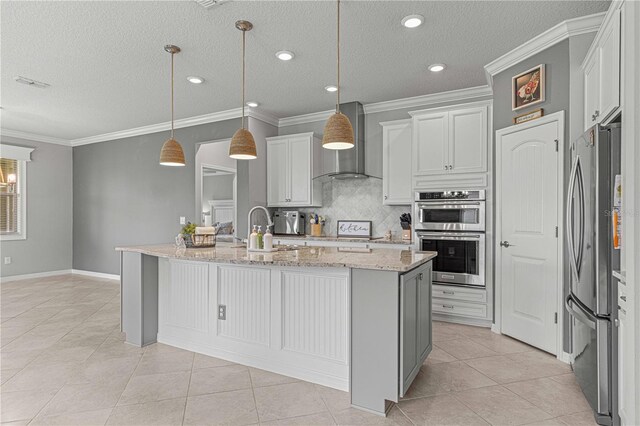 kitchen featuring crown molding, wall chimney exhaust hood, light tile patterned flooring, and appliances with stainless steel finishes