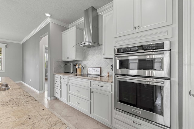 kitchen with light tile patterned floors, decorative backsplash, crown molding, double oven, and wall chimney range hood