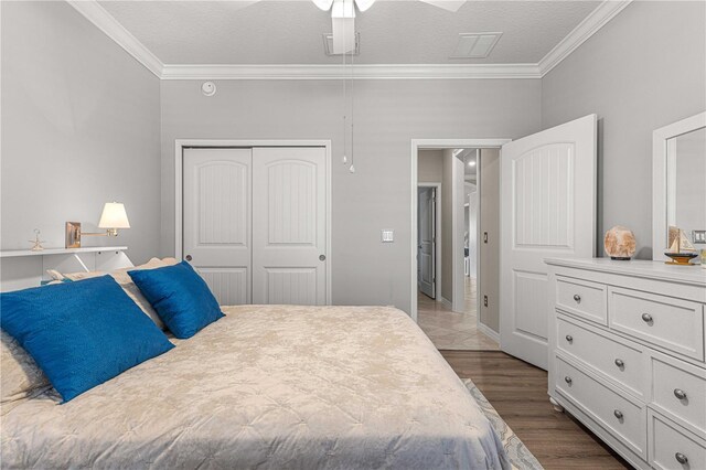 bedroom featuring ceiling fan, ornamental molding, wood finished floors, a closet, and a textured ceiling