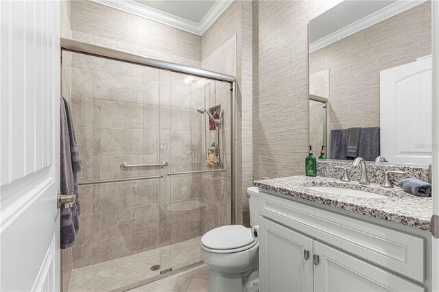 bathroom with toilet, tile patterned flooring, ornamental molding, vanity, and a shower with door