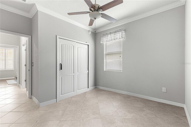 unfurnished bedroom featuring ornamental molding, light tile patterned floors, ceiling fan, and a closet