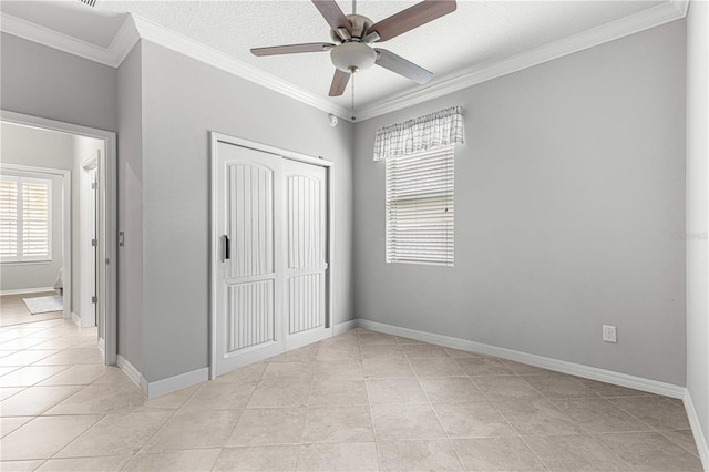unfurnished bedroom with ornamental molding, a textured ceiling, a closet, light tile patterned floors, and baseboards