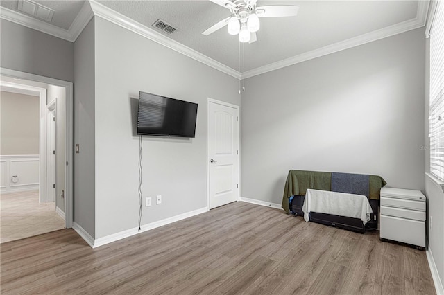 bedroom featuring a ceiling fan, wood finished floors, visible vents, and ornamental molding