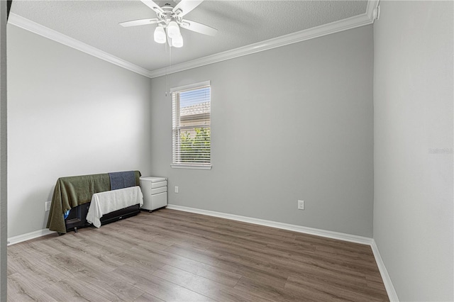 spare room with baseboards, wood finished floors, a ceiling fan, and crown molding