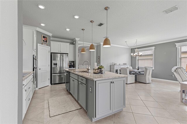 kitchen featuring pendant lighting, stainless steel appliances, a center island with sink, and sink