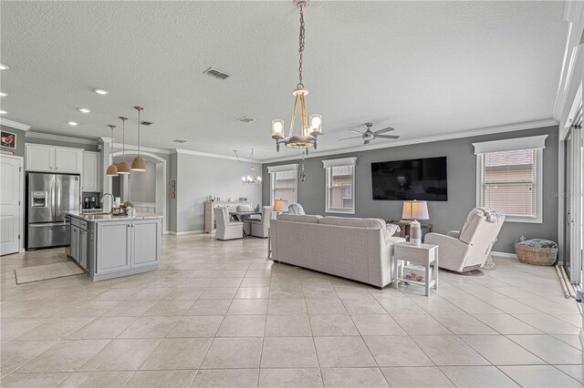 living room with ceiling fan with notable chandelier, crown molding, and light tile patterned flooring