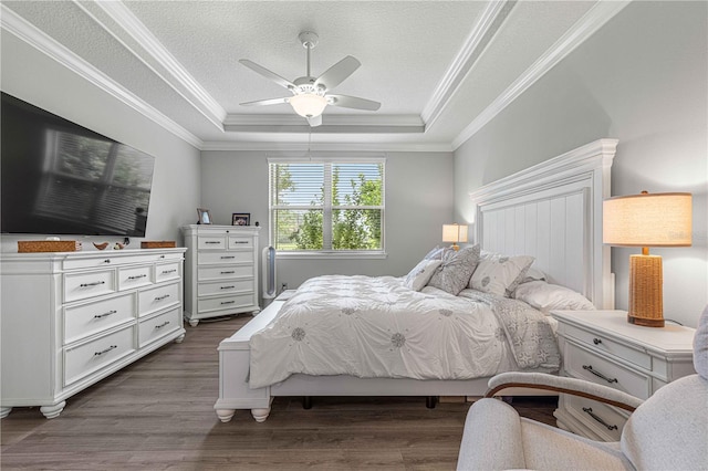 bedroom featuring crown molding, ceiling fan, a tray ceiling, dark wood-style floors, and a textured ceiling