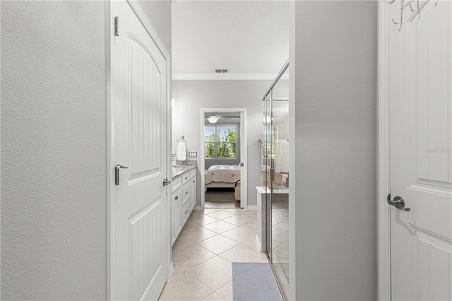 interior space with walk in shower, tile patterned floors, ornamental molding, vanity, and ceiling fan