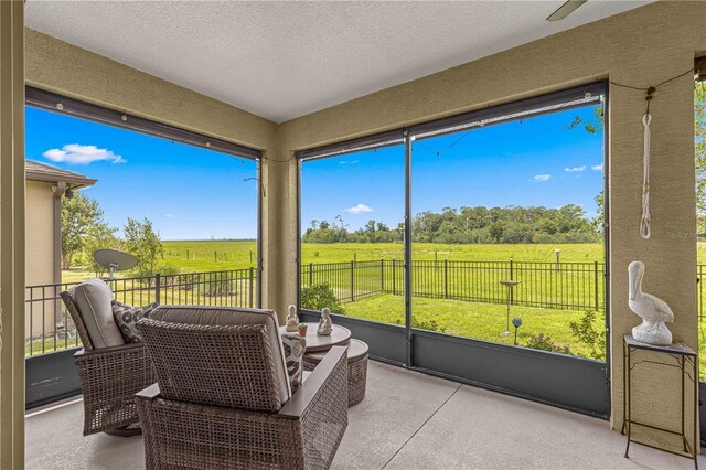 sunroom / solarium with ceiling fan and a rural view