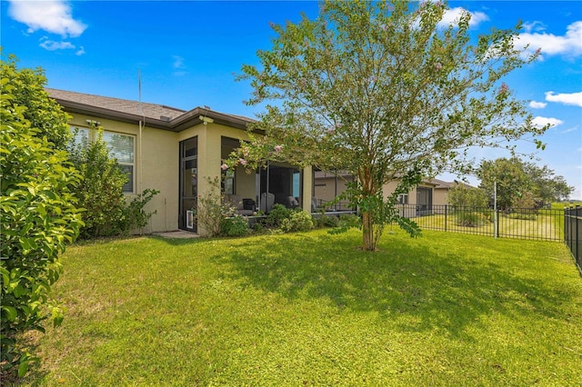 back of property with stucco siding, a lawn, and fence