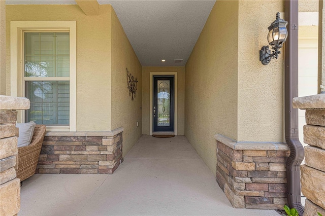 doorway to property featuring visible vents and stucco siding