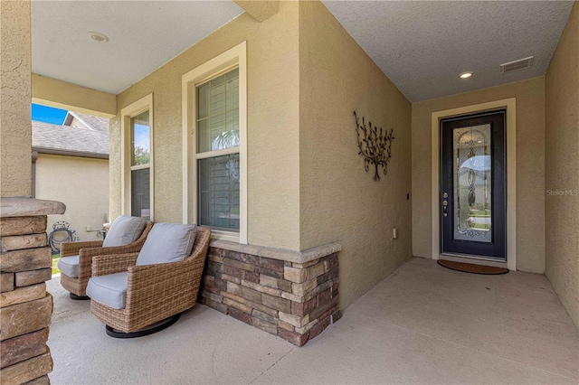 entrance to property with visible vents and stucco siding