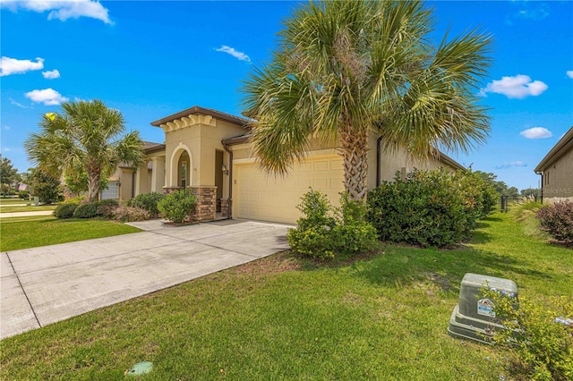 mediterranean / spanish home featuring a front yard, driveway, stucco siding, stone siding, and a garage