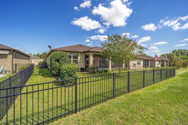 view of front of home featuring a front lawn, a fenced backyard, and stucco siding