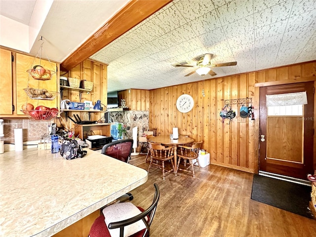 kitchen with ceiling fan, hardwood / wood-style flooring, and wooden walls