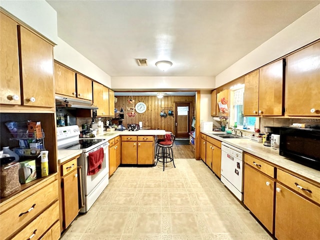 kitchen featuring white appliances, light countertops, under cabinet range hood, and a peninsula