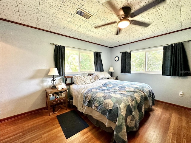 bedroom featuring ornamental molding, multiple windows, ceiling fan, and hardwood / wood-style flooring