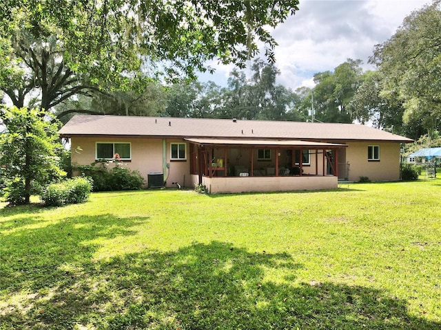 rear view of property with a lawn and central AC