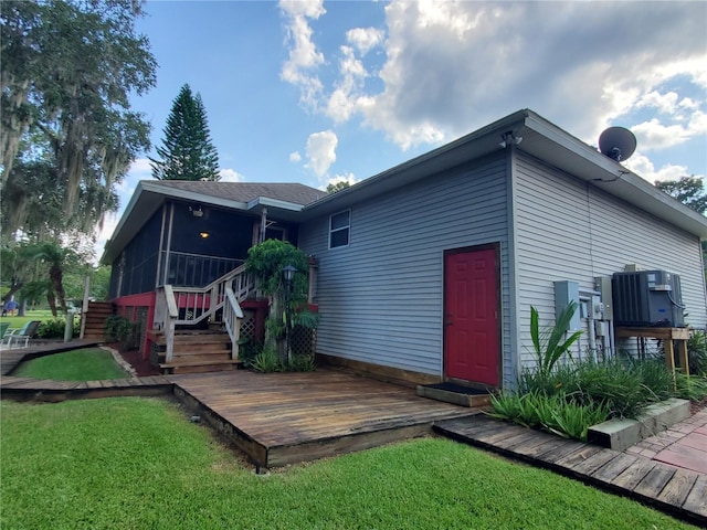 rear view of house featuring a wooden deck and a yard