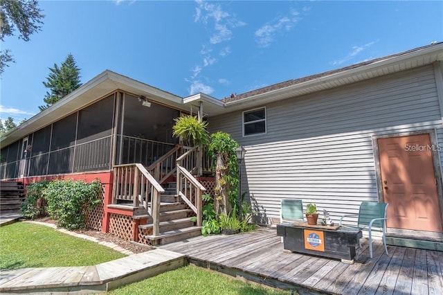 rear view of property with a sunroom and a deck