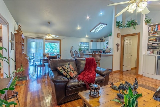 living room with ceiling fan, light hardwood / wood-style flooring, and vaulted ceiling