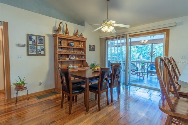 dining area featuring ceiling fan, wood-type flooring, and vaulted ceiling