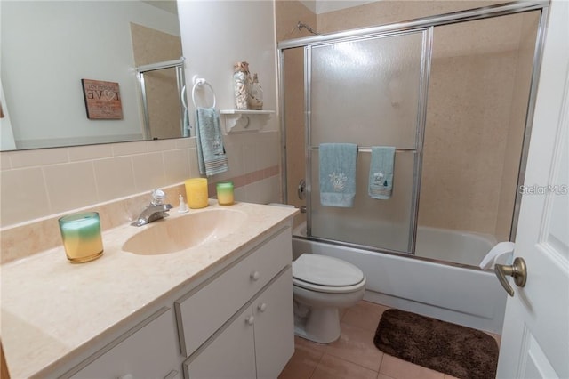 full bathroom featuring decorative backsplash, toilet, tile patterned floors, vanity, and bath / shower combo with glass door