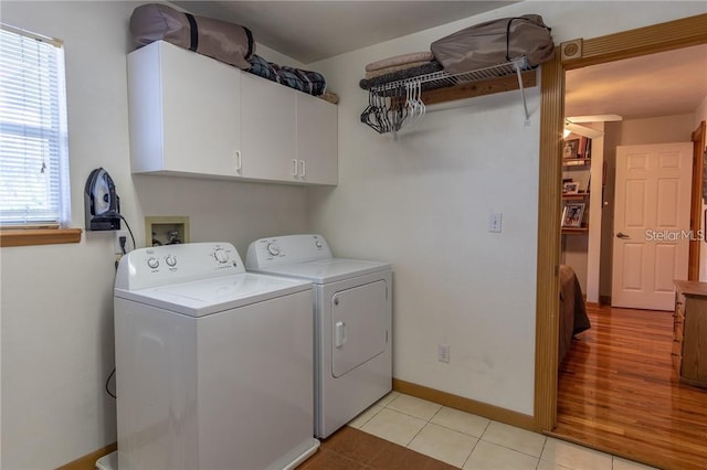 laundry room featuring light hardwood / wood-style flooring, washing machine and clothes dryer, and cabinets