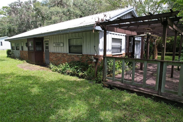 view of property exterior featuring metal roof, brick siding, a lawn, a pergola, and board and batten siding