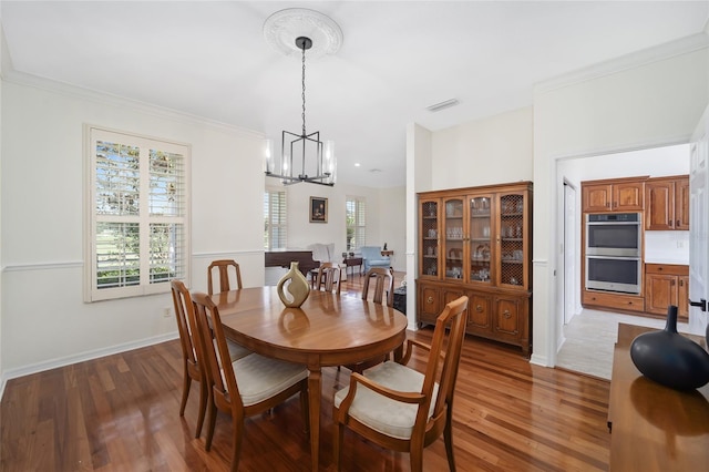 dining area featuring a notable chandelier, crown molding, and hardwood / wood-style flooring