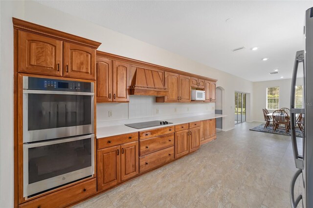 kitchen with appliances with stainless steel finishes, tasteful backsplash, and custom exhaust hood