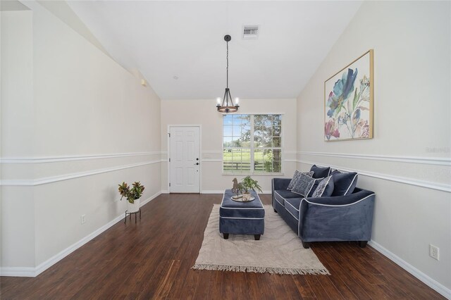 living area featuring dark hardwood / wood-style flooring, lofted ceiling, and a chandelier