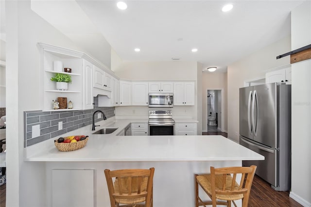 kitchen featuring a breakfast bar, kitchen peninsula, appliances with stainless steel finishes, and sink