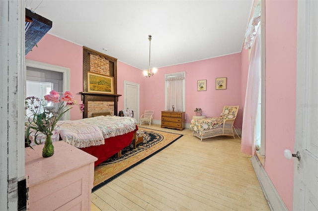 bedroom featuring brick wall, a chandelier, and light wood-type flooring