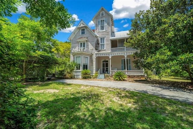 view of front of property with a balcony, a porch, and a front yard