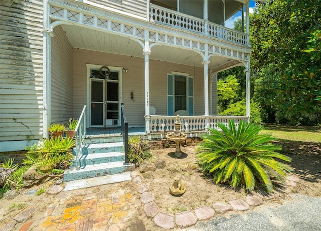 view of exterior entry with a porch and a balcony