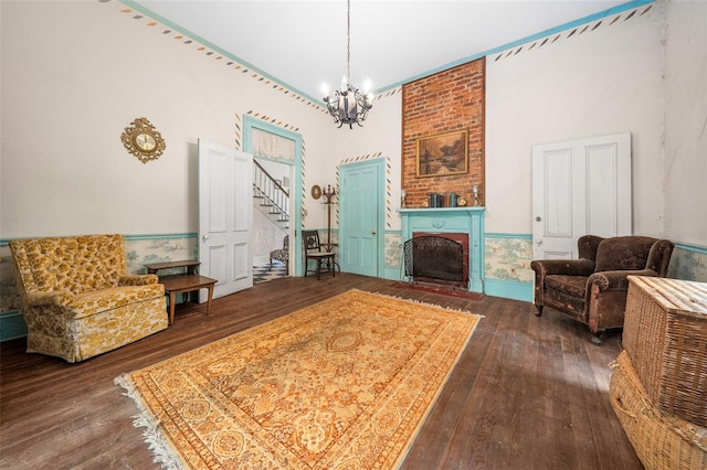 living room featuring brick wall, dark wood-type flooring, a chandelier, and a brick fireplace