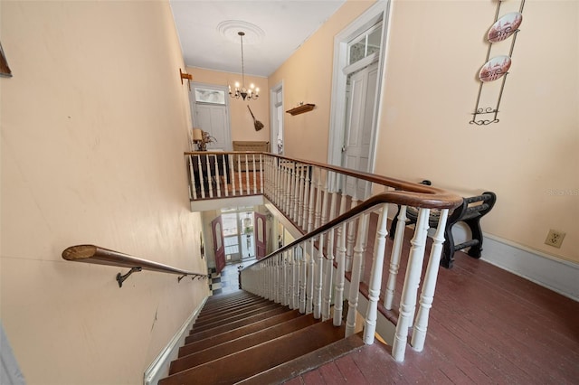 stairs featuring dark hardwood / wood-style floors and a chandelier