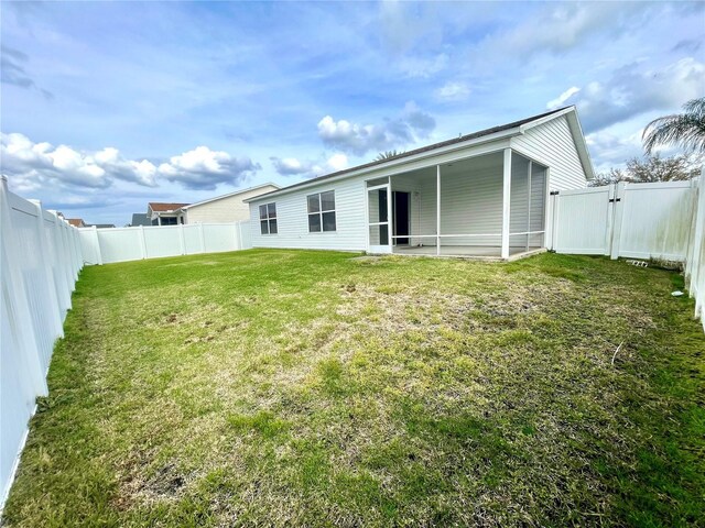 rear view of property with a gate, a fenced backyard, and a yard