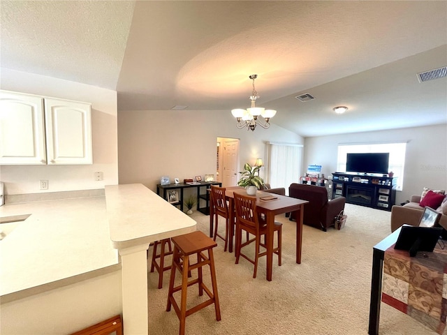 dining area with visible vents, an inviting chandelier, light carpet, vaulted ceiling, and a textured ceiling