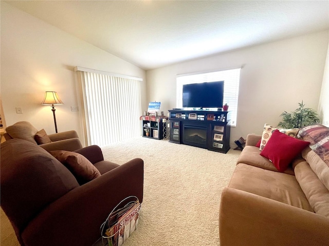 carpeted living room with lofted ceiling and a glass covered fireplace