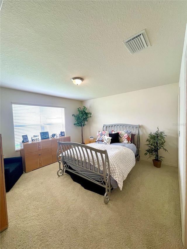 carpeted bedroom with visible vents and a textured ceiling