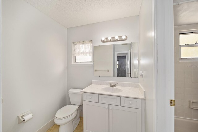 bathroom with vanity, toilet, plenty of natural light, and a textured ceiling