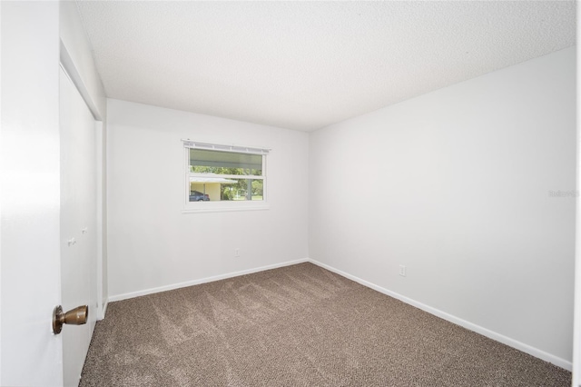 carpeted empty room featuring a textured ceiling