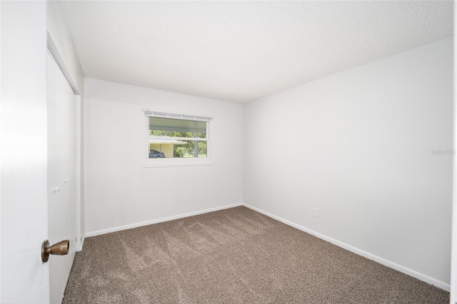 carpeted spare room featuring baseboards and a textured ceiling