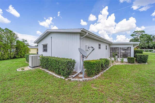 view of side of property featuring central AC unit and a lawn