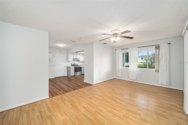 unfurnished living room featuring light wood-style floors, a ceiling fan, baseboards, and a textured ceiling